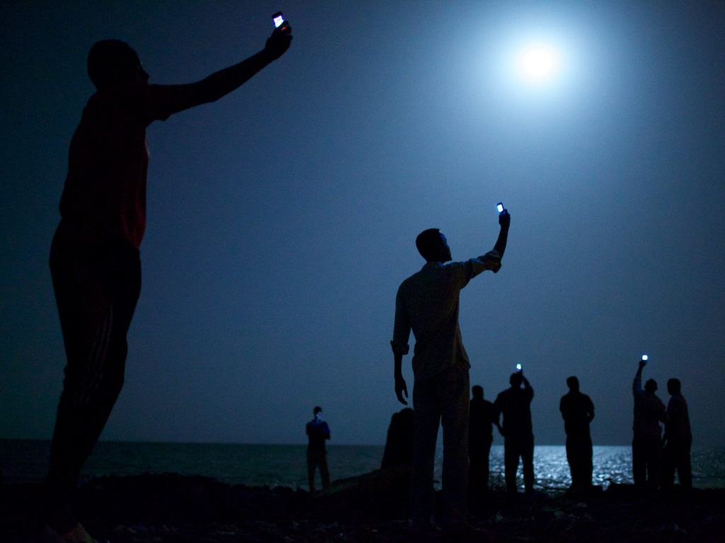 Снимка на американеца Джон Станмайър с африкански имигранти, протегнали телефоните си към небето с надеждата да уловят мрежа за последен път, спечели първа награда на най-престижния конкурс за фотожурналистика