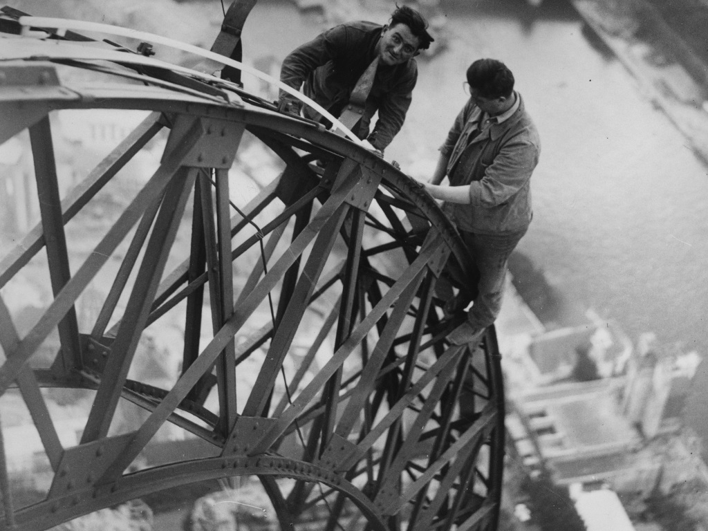 Високо над река Сена, двама електротехници работят върху осветлението на Айфеловата кула, която ще свети през нощта в Париж - 29 октомври 1937 г.