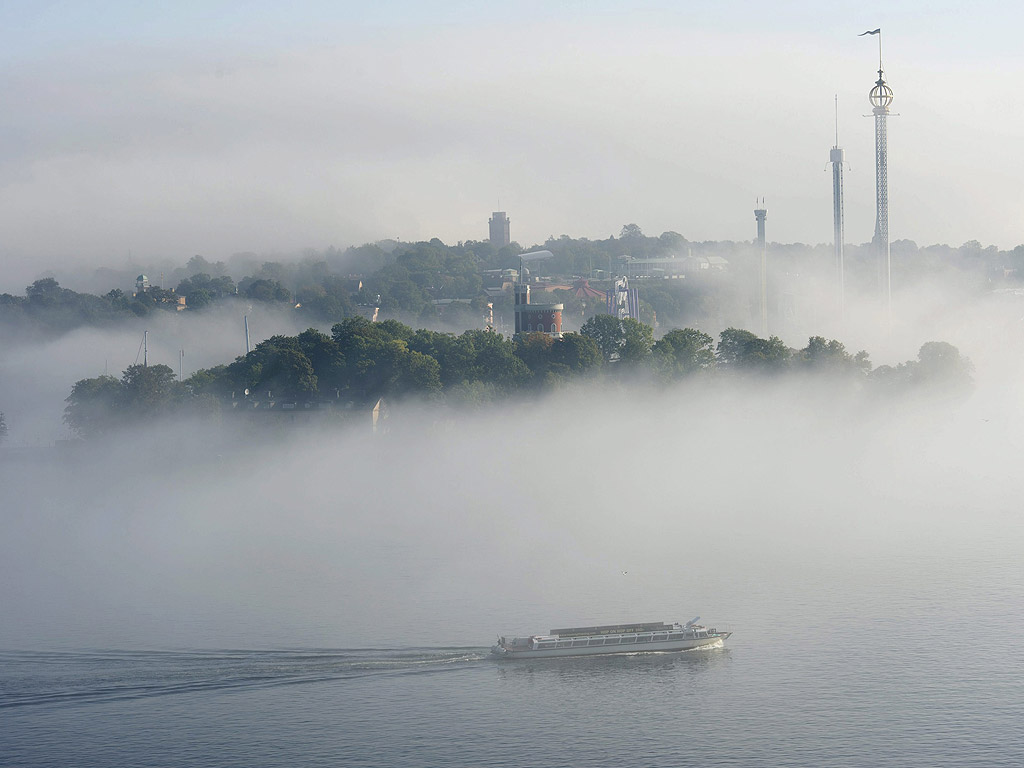 Лодка се движи през гъста мъгла в центъра на Стокхолм, Швеция.