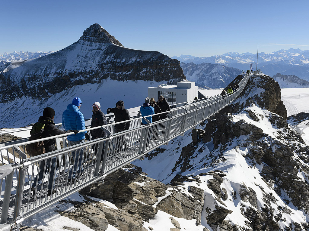 Хора ходят по висящ мост в ледника Les Diablerets, Швейцария. Алеята e с дължина 107 м и ширина 80 см и предлага зашеметяваща гледка към Алпите