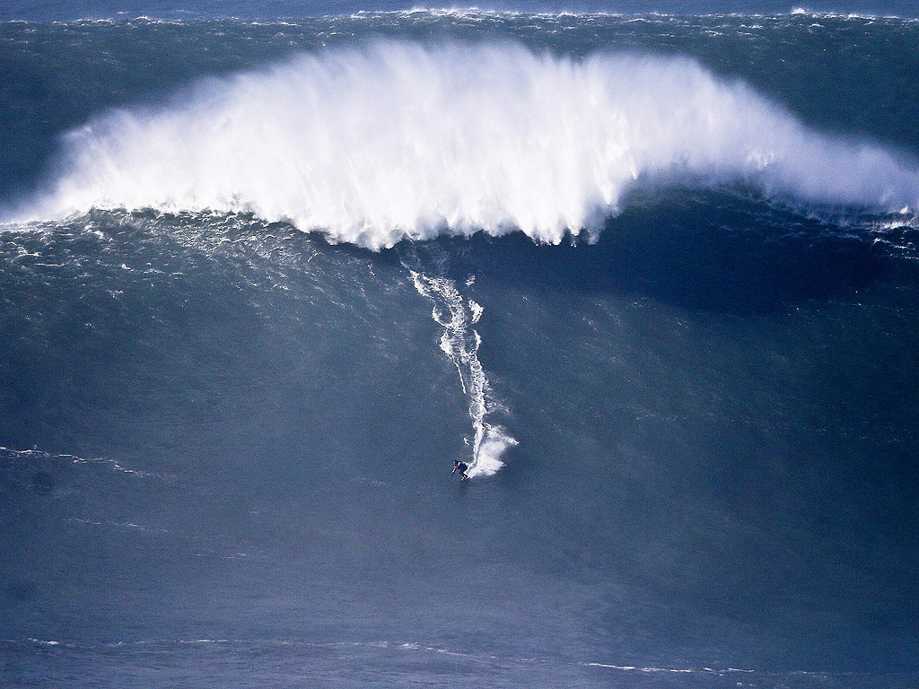 11 декември. Сърфист се спуска по огромна вълна на Прая до Норте в Назаре, Португалия.