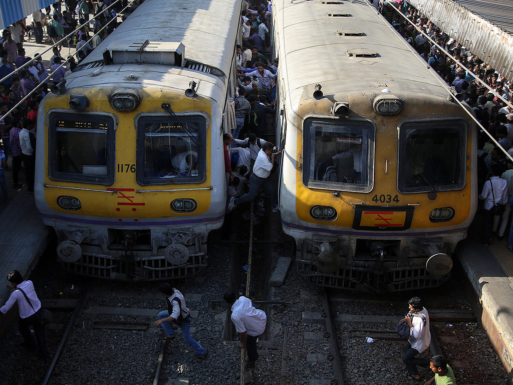 Индийци се катерят върху влак на жп гара в Мумбай, Индия.
