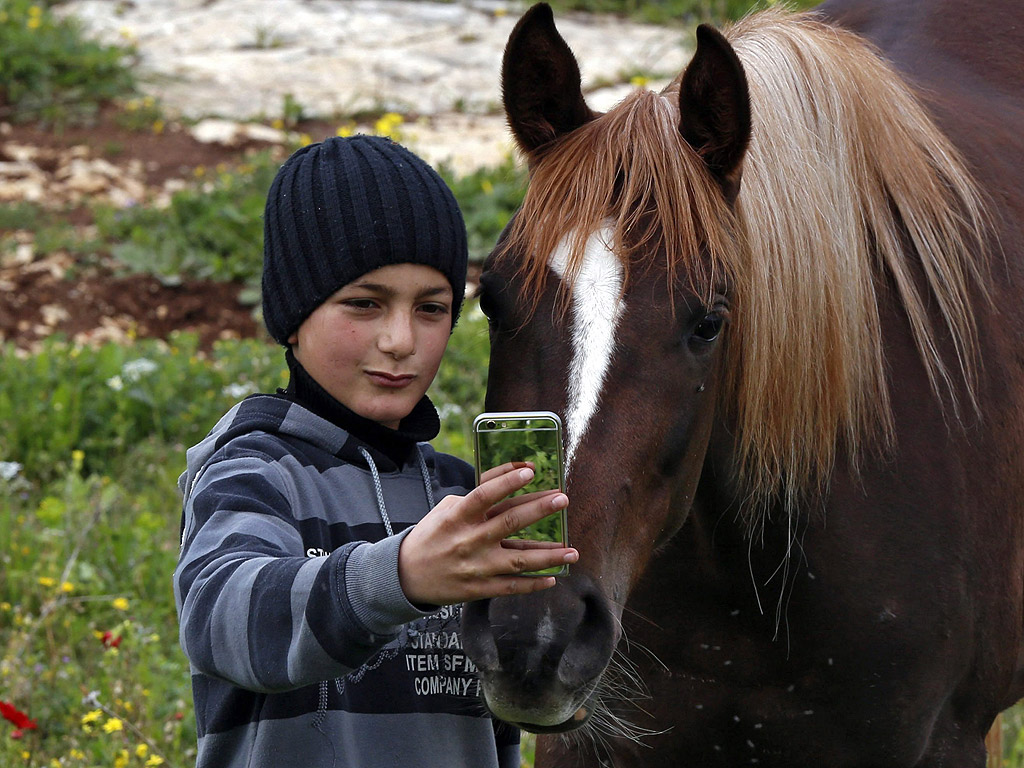 Палестинско момче прави селфи с кон в семейната си ферма близо до Наблус