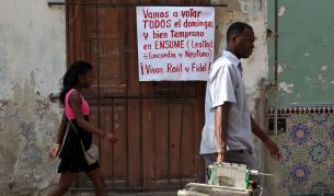 Кубинци минават покрай плакат за изборите