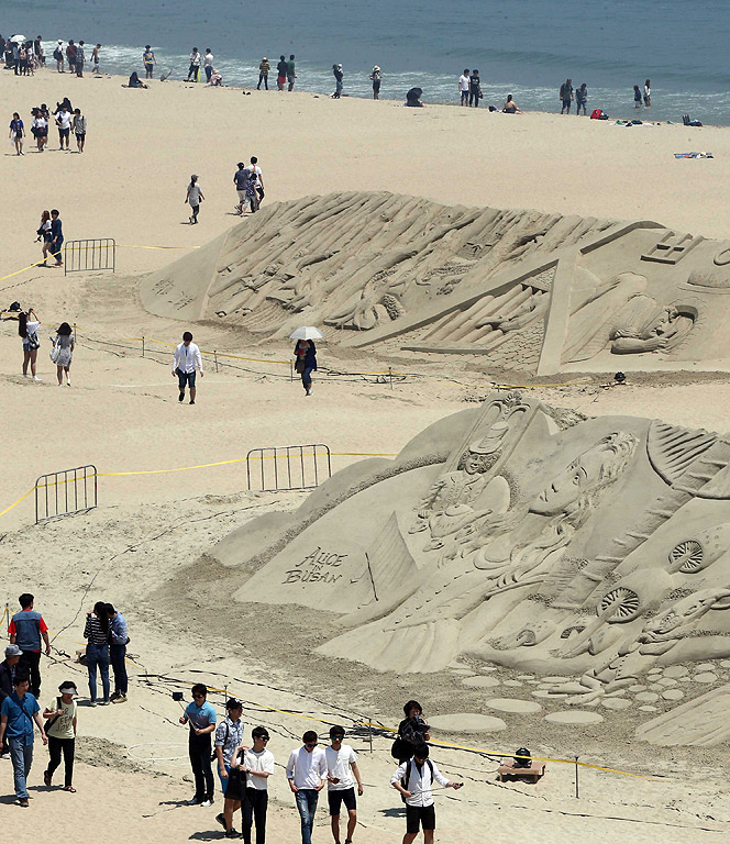 Хора разглеждат пясъчните скулптури в югоизточния град Бусан, Южна Корея, по време на четири дневния пясъчен фестивал включващ сцени от известни приказки, като Пинокио, Питър Пан и Магьосникът от Оз
