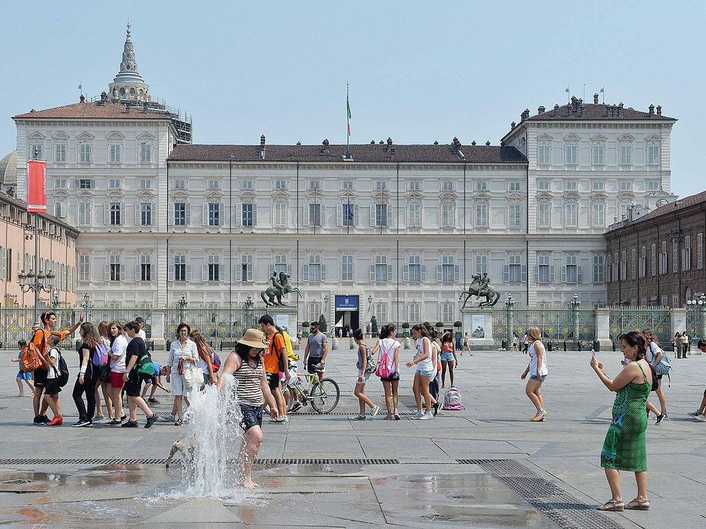 Хора се разхлаждат от жегата край фонтан пред Кралския дворец в Торино, Северна Италия