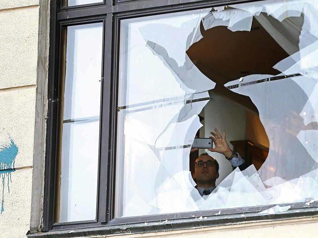 Служител снима счупен прозорец на турското посолство по време на протест на руснаците пред посолството на Турция в Москва, Русия