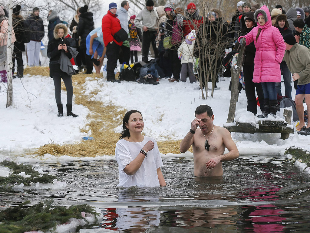 Православни вярващи се къпят в студена вода по време на Богоявленски тържества в Киев, Украйна. По време на Богоявление, някои хора вярват, че водите имат специални лечебни свойства и могат да бъдат използвани за лечение на различни заболявания, а много от тях правят ледени бани, като част от празника