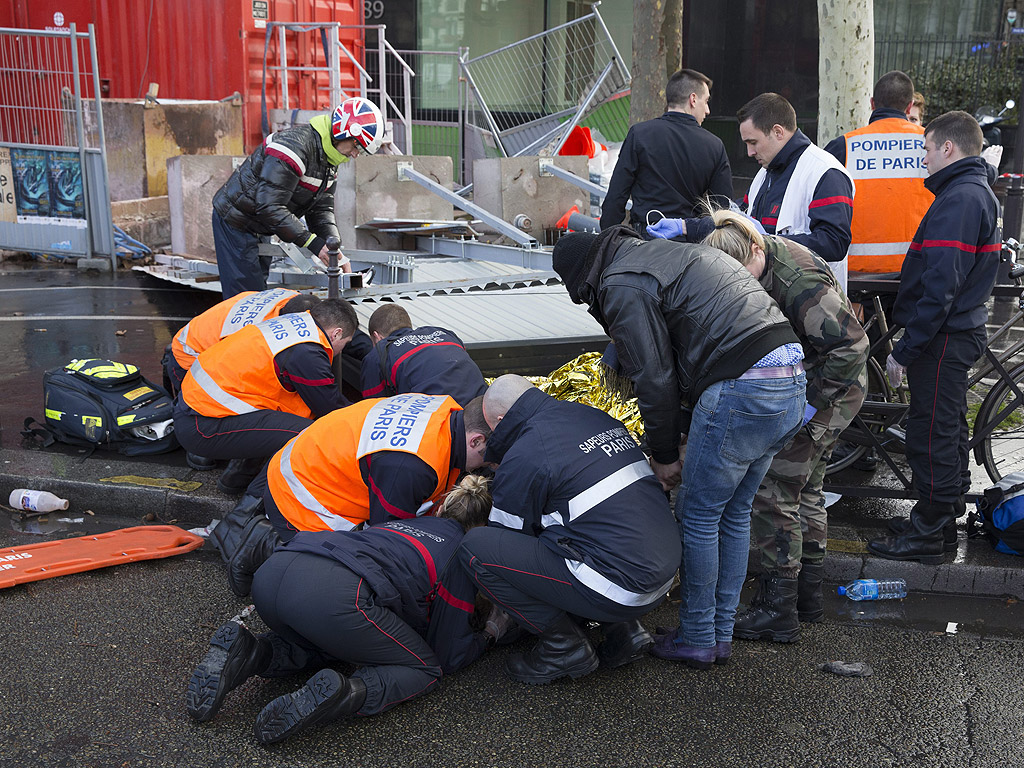 Пожарна и спасителните служби, осигуряват първа помощ на лице, увредено след като билборд падна поради силни ветрове, в Париж, Франция.