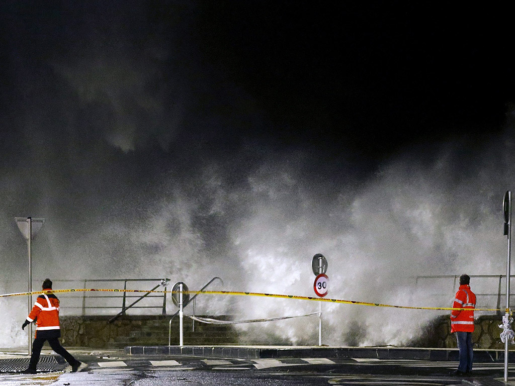 Членовете на аварийните служби гледат вълните в Пасео Нуево, Сан Себастиан, северна Испания. Червен код е обявен в северната част на страната и се очакват силни ветрове и огромни вълни
