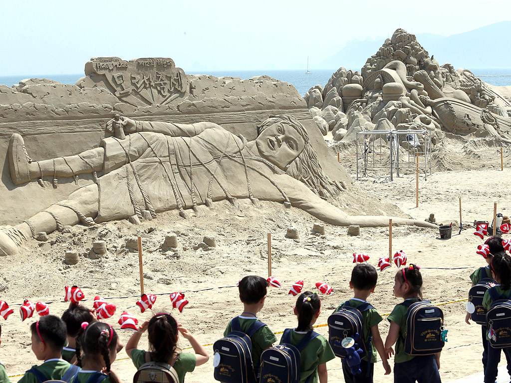 Деца разглеждат пясъчна скулптура, изобразяваща сцена от приказката "Пътешествията на Гъливер" на плаж в югоизточния град Бусан, Южна Корея.