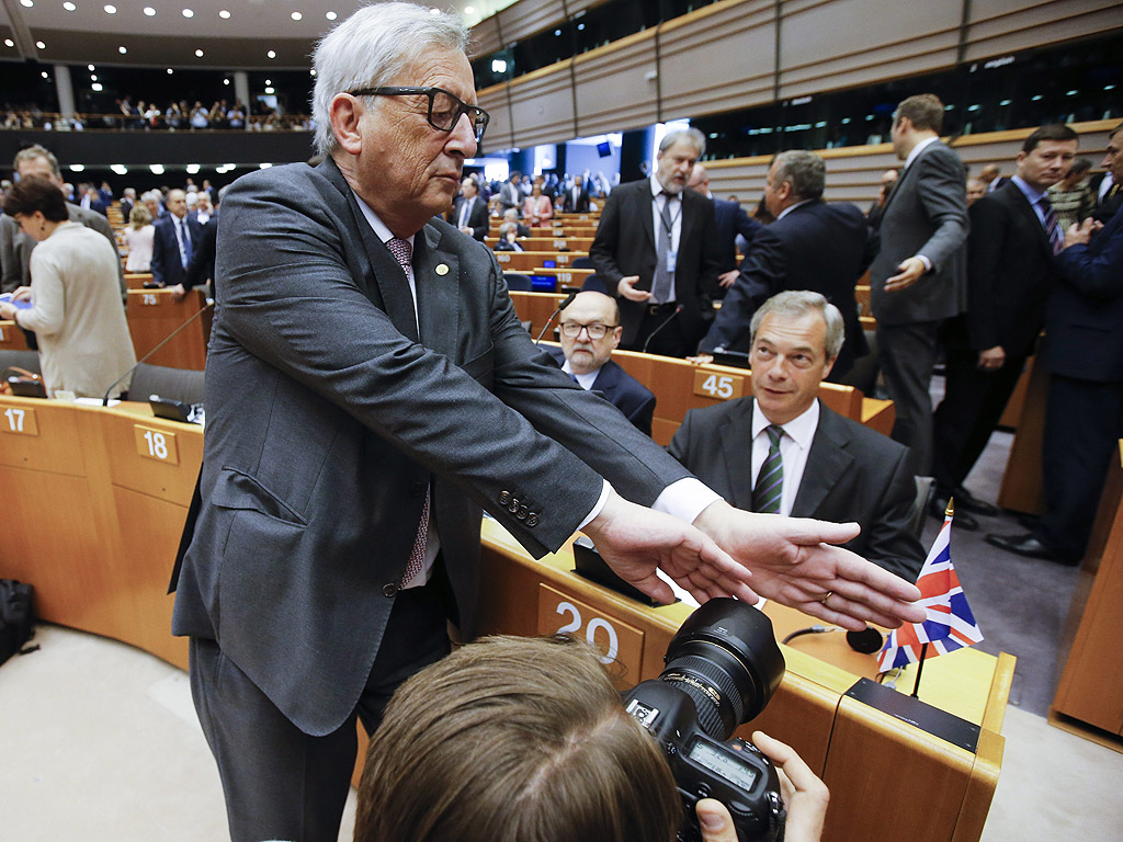 Председателят на Европейската комисия Жан-Клод Юнкер се опитва да попречи на фотограф да снима Найджъл Фараж, лидер на Британската партия на независимостта (UKIP), преди началото на пленарната сесия на Европейския парламент, в Брюксел, Белгия