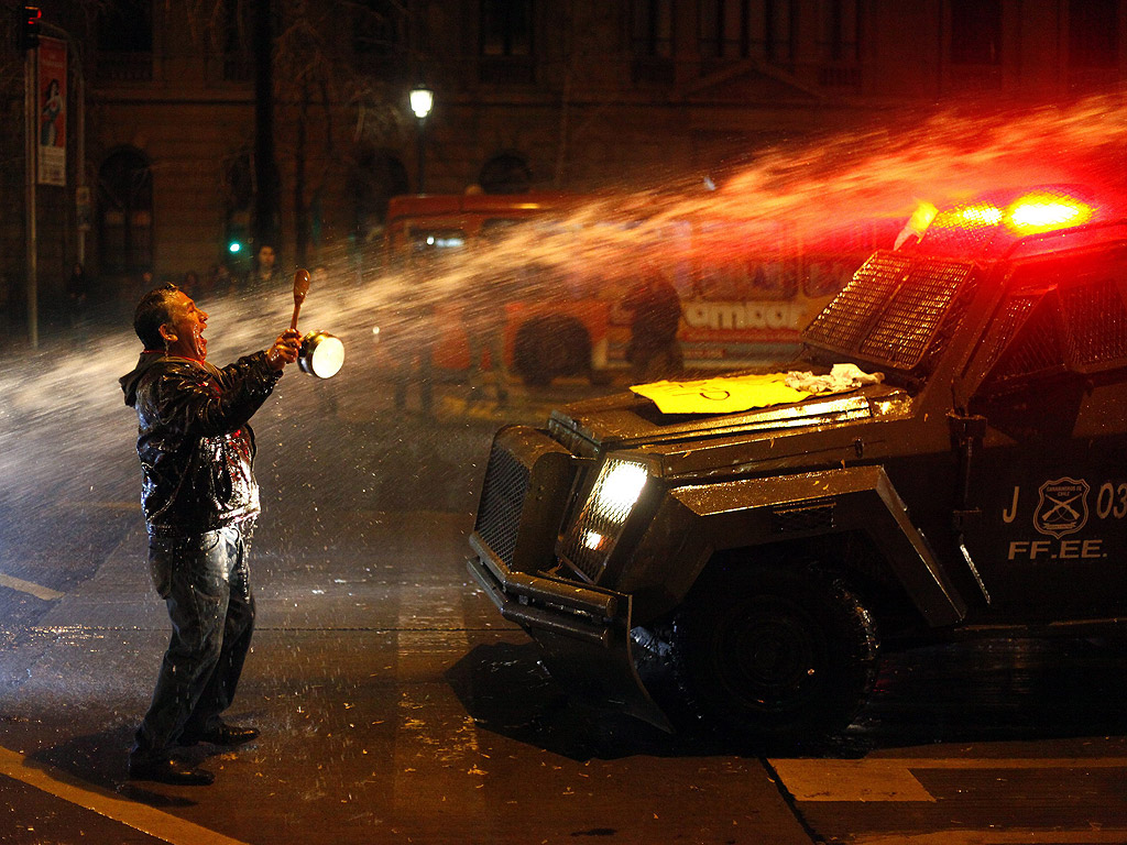Демонстрант е ударен от водна струя от полицейски камион, при опита на полицейските отряди да контролират протестиращи срещу пенсионната система в Сантяго, Чили