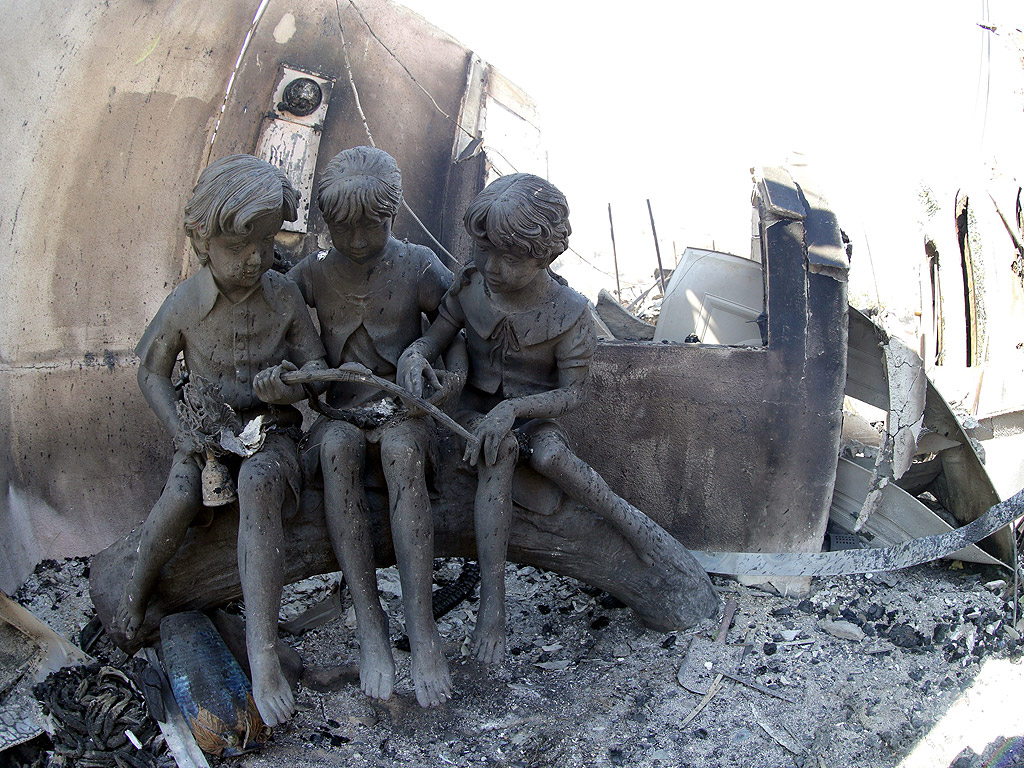 Статуя на три деца е всичко, което остана от една изгоряла къща в близост до Фелан, Калифорния, САЩ. Над 30 000 декара горят унищожени са десетки жилища, над 80 000 души са евакуирани в окръг Сан Бернардино
