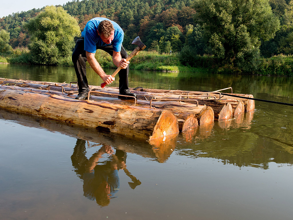 Салджията Хайнц Кристиян работи по смърчови трупи в река Везер за реконструкция на исторически сал в Рейнхардсхаген, Германия.