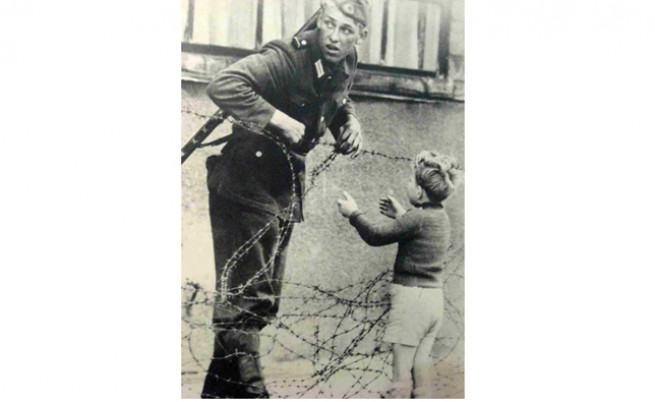  Войникът от Източен Берлин оказва помощ на дребното момченце. 