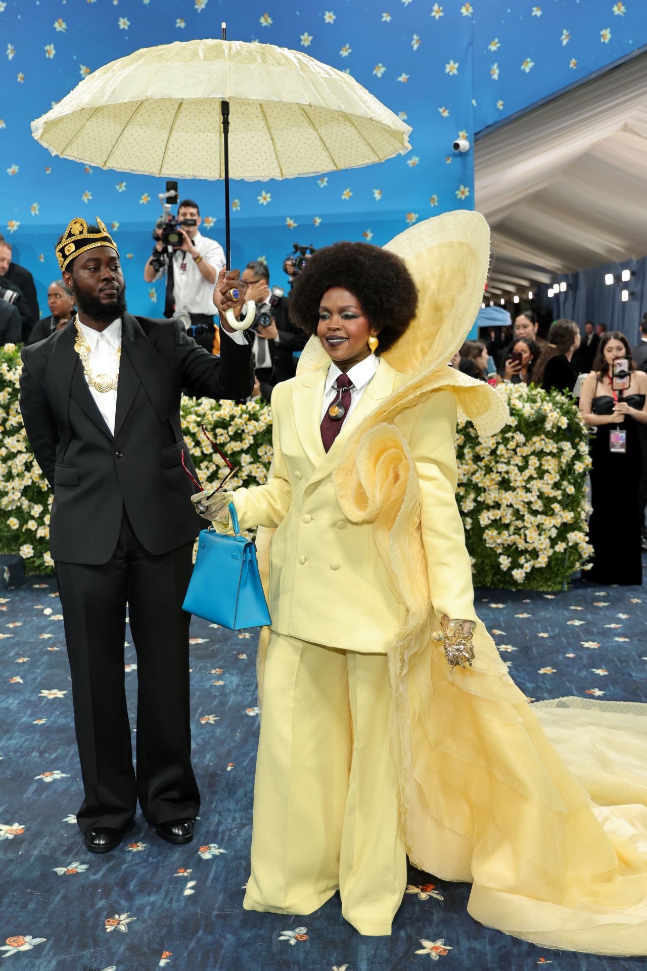 <p>Лорин Хил се появи за първи път на Met Gala в жълт костюм и подходящ шлейф. Бижутата ѝ, създадени от бижутера и куратор Емефа Коул, отдадоха почит на ганайските кралски особи.</p>