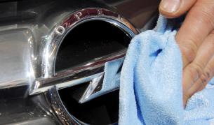 Служител почиства емблемата на експонат от изложението в Женева