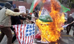 Подръжници на Ахмадинеджад горят британско, американско и израелско знаме пред посолството на Великобритания в Техеран.