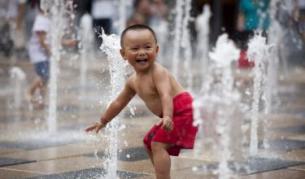Китайче се наслаждава на прохладата от фонтаните през юли т.г., когато температурите в Пекин стигнаха 35 градуса