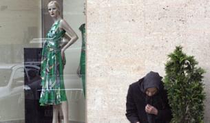 Възрастна жена проси пред лъскав бутик в центъра на София