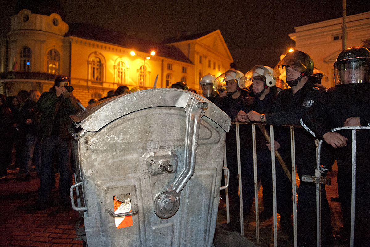 Малко след 19 ч. демонстрантите засилиха контейнери за боклук към металните ограждения пред парадния вход на сградата, а след това започнаха да дърпат преградите и успяха да ги разкъсат.