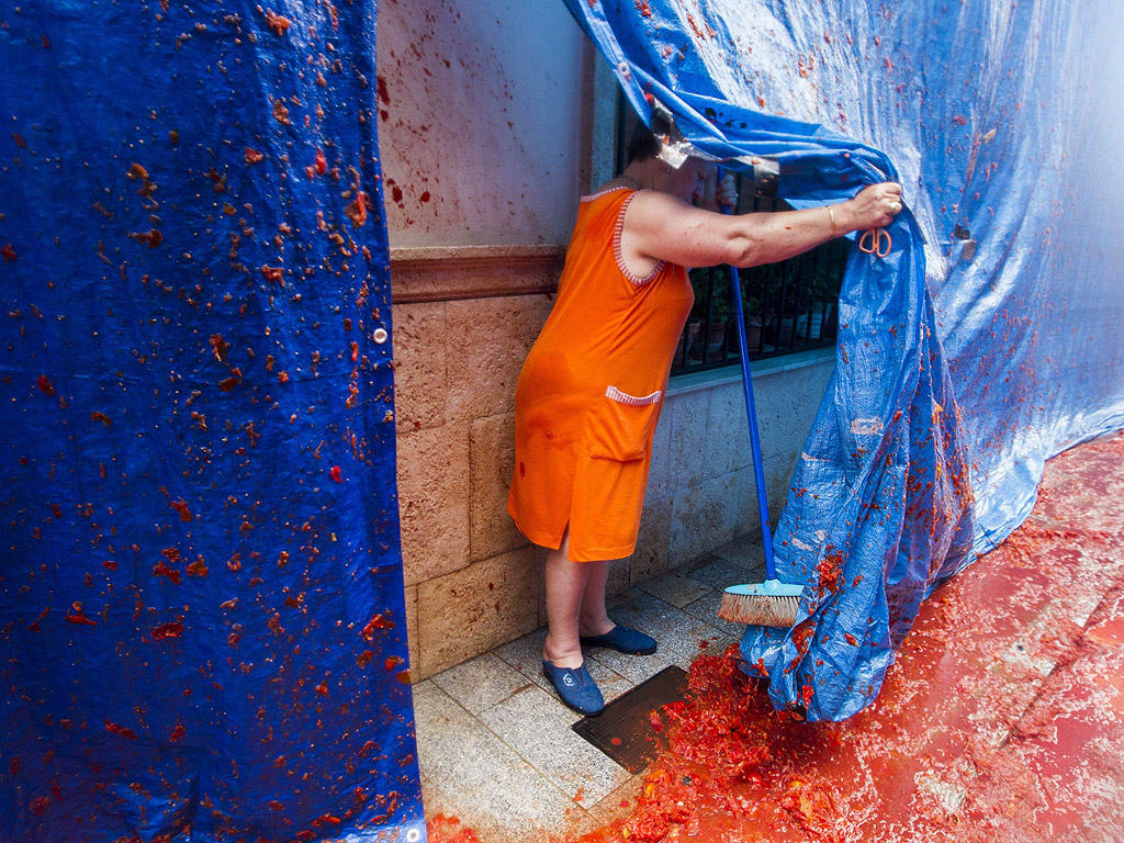 Жена чисти след Томатина – празникът, на който испанците се бият с домати, в Бунол, Испания, на 28 август. Тази година общината в Бунол продаде 15 хиляди билета на чужденци, които, заедно с 5000 местни жители, които не плащат, за да участват в боя, са хвърлили 130 тона домати.